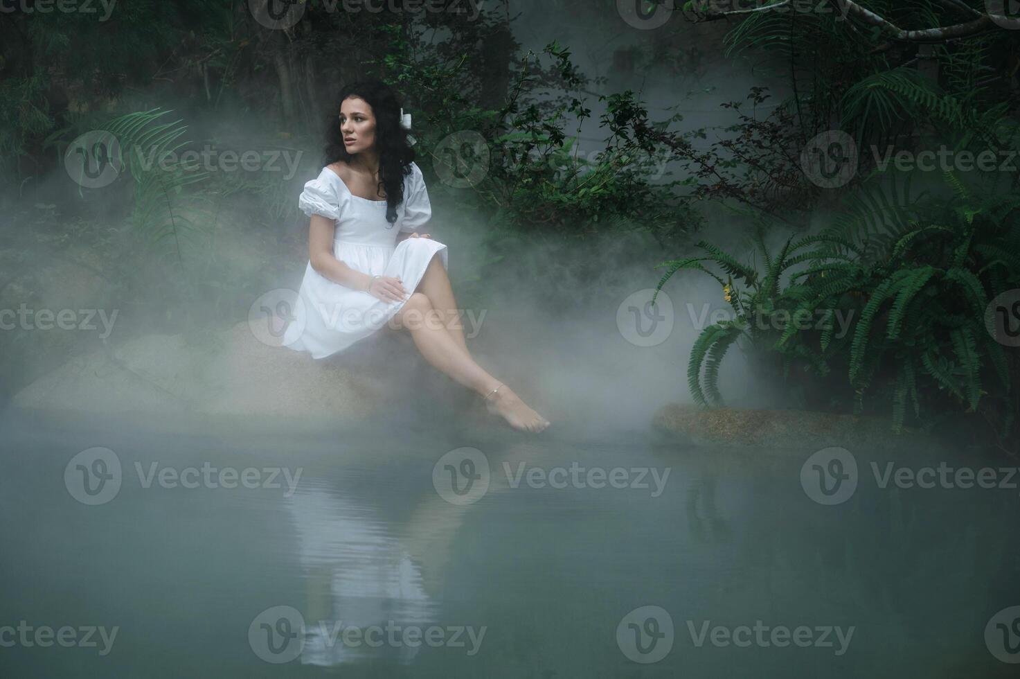 A princess or fairy in a mystical garden by the lake surrounded by trees and fog. Fairyland photo