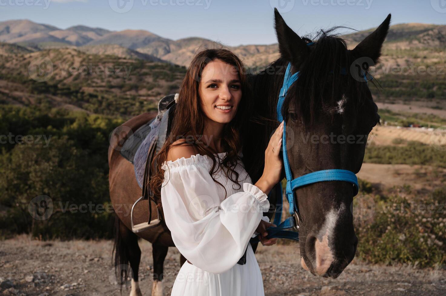 Close-up. A romantic girl hugs her horse against the backdrop of a mountain-plain landscape. The concept of riding. Artistic photography. Ready-made cover for books and magazines. photo