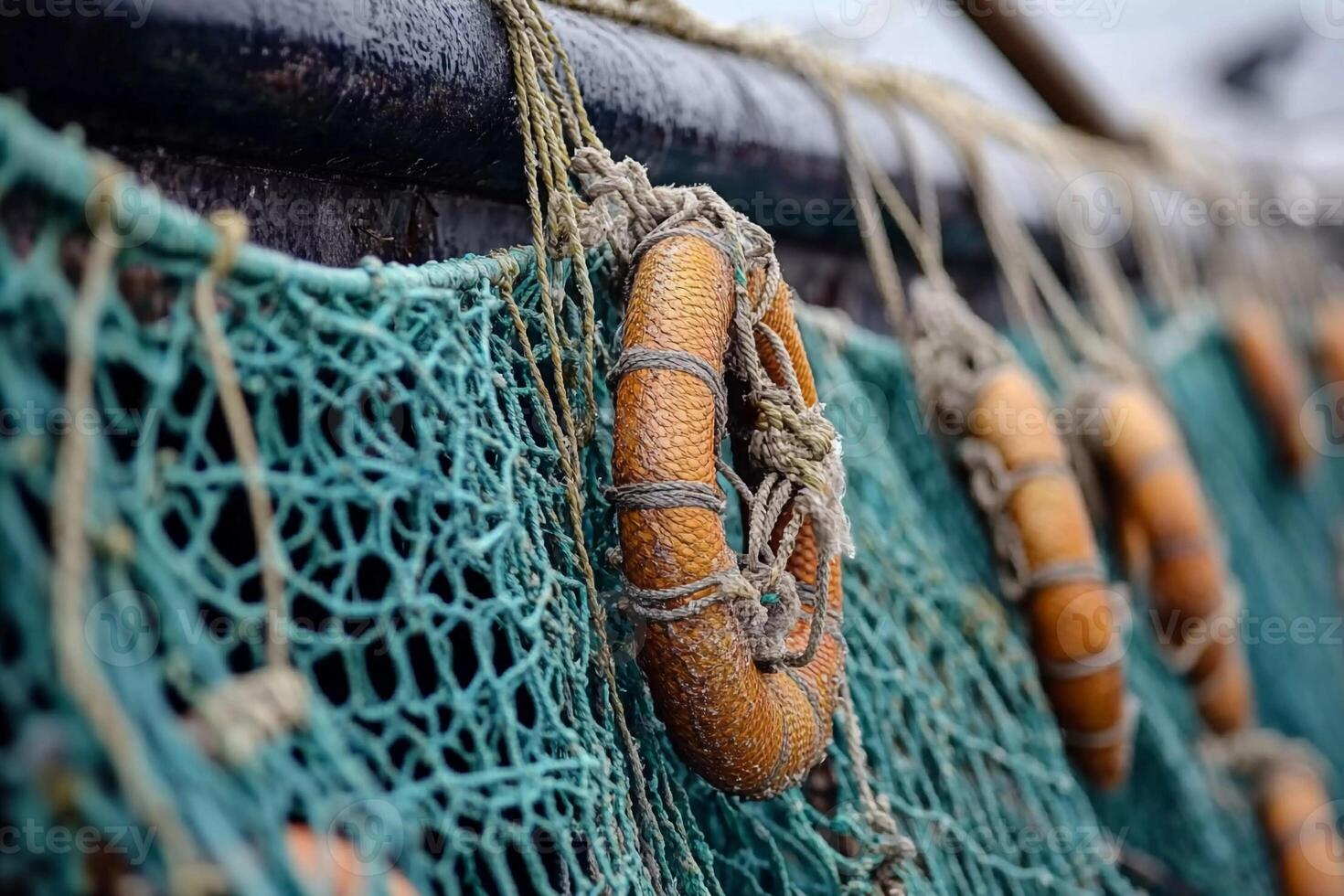 Lifebuoys hanging on fishing nets under overcast skies at the harbor during early morning hours photo