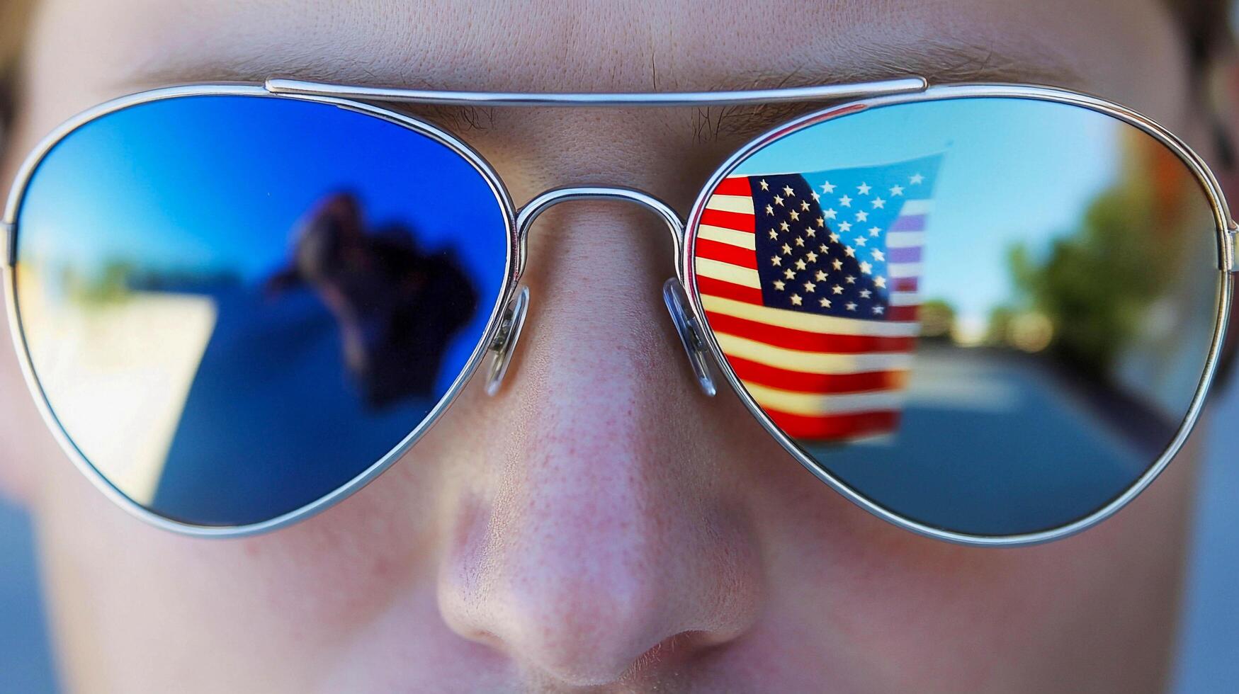 A man wearing sunglasses with an american flag reflected in them photo