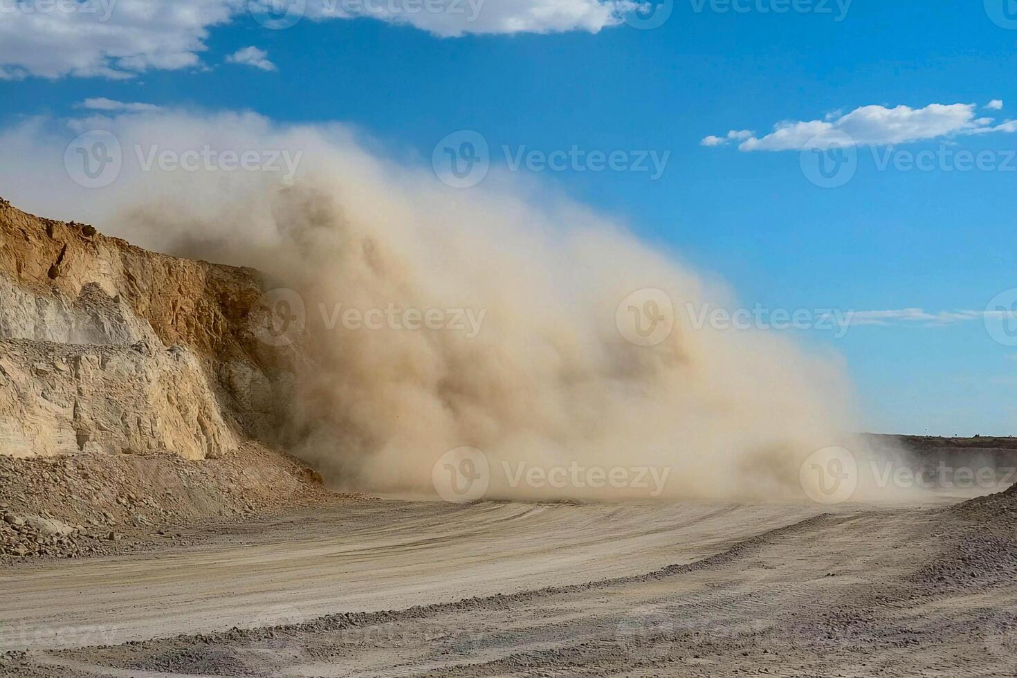 A large dust cloud is blowing in front of a large rock wall photo