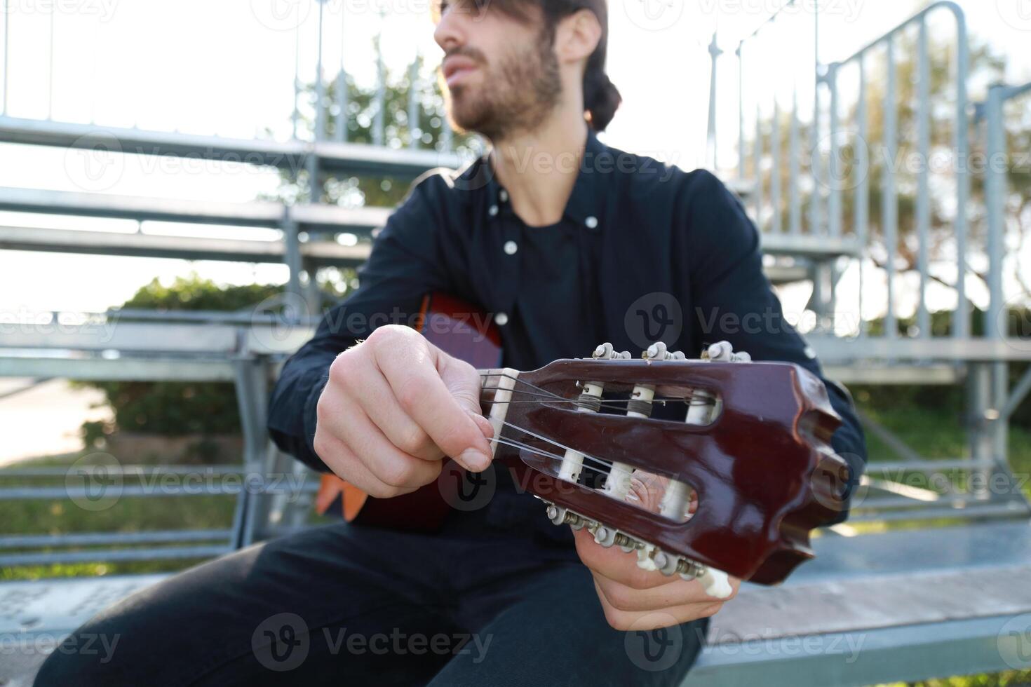 Hand Of MAn Turns Wrench For Manual Tuning Of Classical Guitar photo