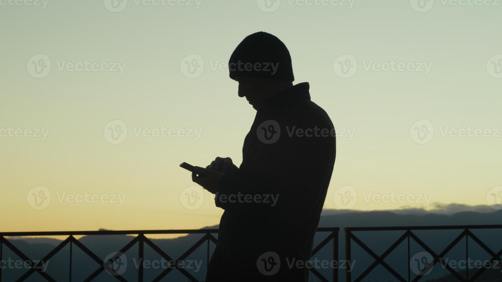 Silhouette Of A Man Scrolling The News On The Phone At Sunset photo