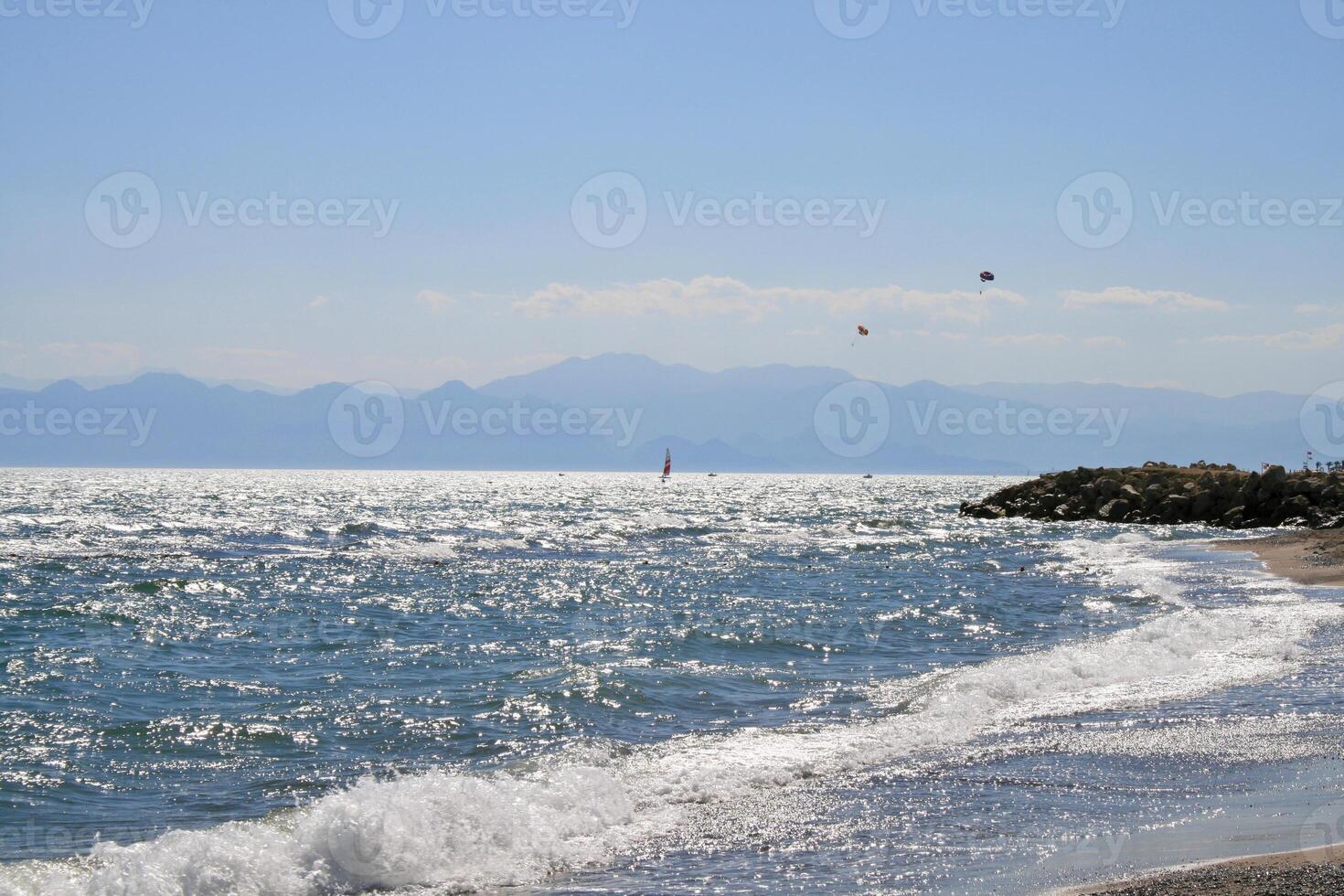 The Mediterranean coastline with a view of the mountains, the sea space shimmers with sun spots on the waves. photo