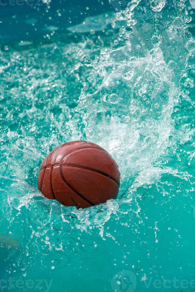 The ball falls into the turquoise water of the pool, creating spectacular splashes and drops. photo