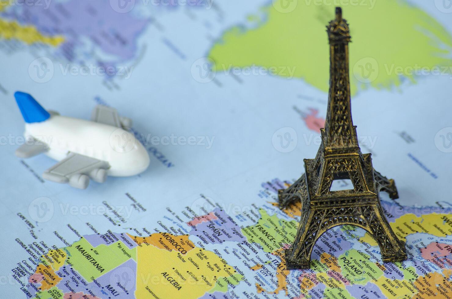 Small toy airplane and a miniature Eiffel Tower placed on a world map. Travel destination concept photo