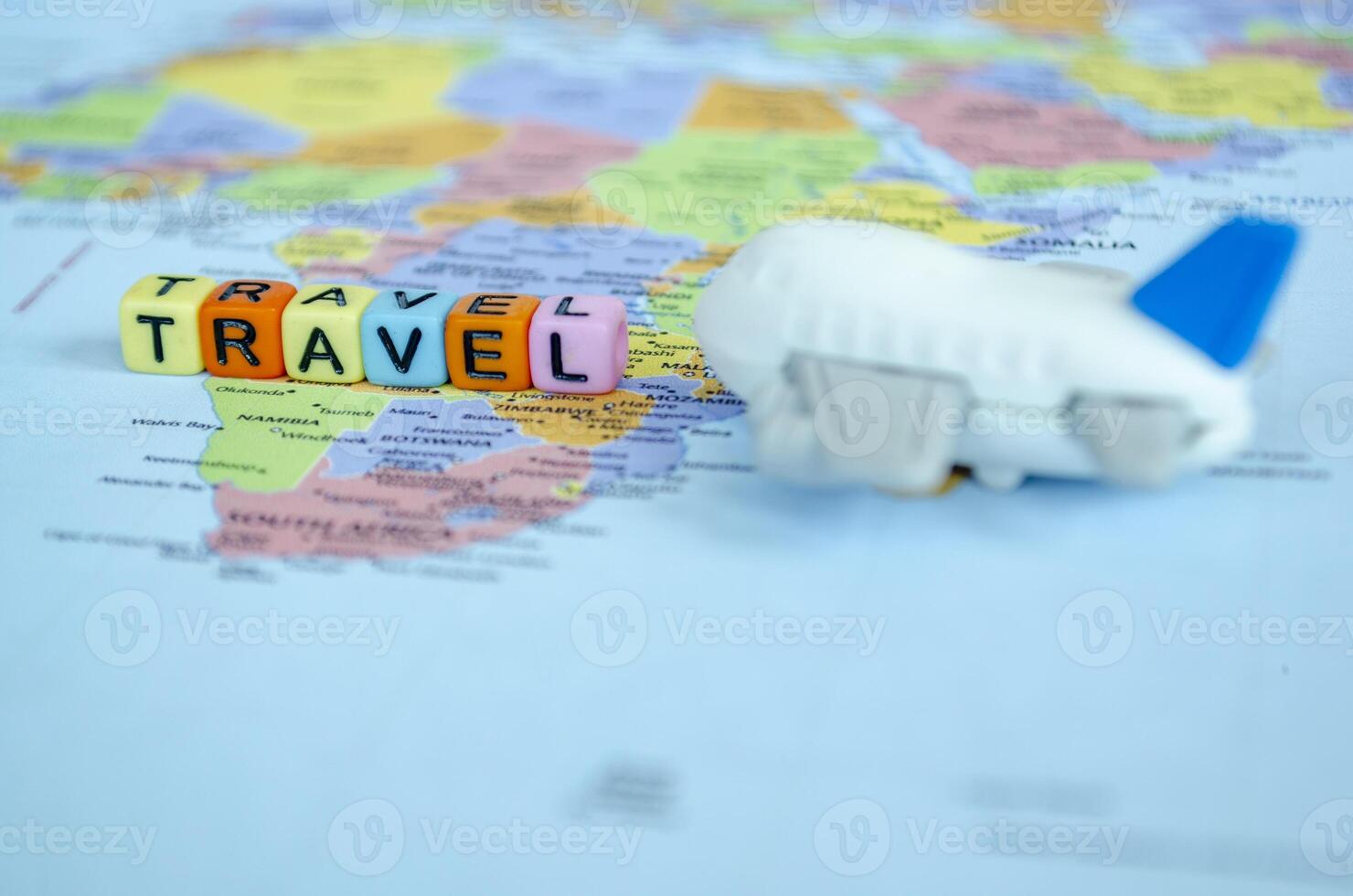 Small plastic cubes with text TRAVEL placed on world map with small airplane. Travel and exploration concept photo