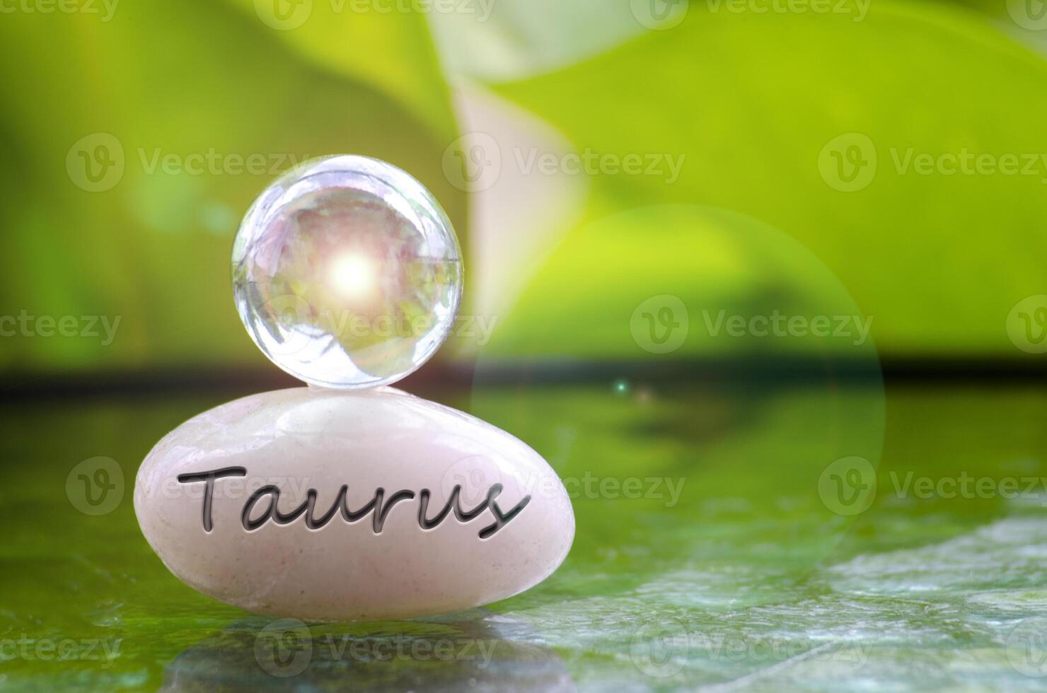 Taurus text engraved on Zen stone with shining glass marble on top. Zodiac concept photo