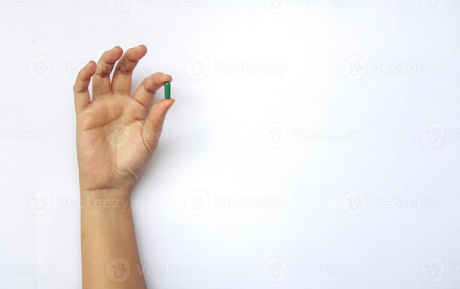 Hand holding green pill or capsule with customizable space for text. Medical and health matters concept. photo