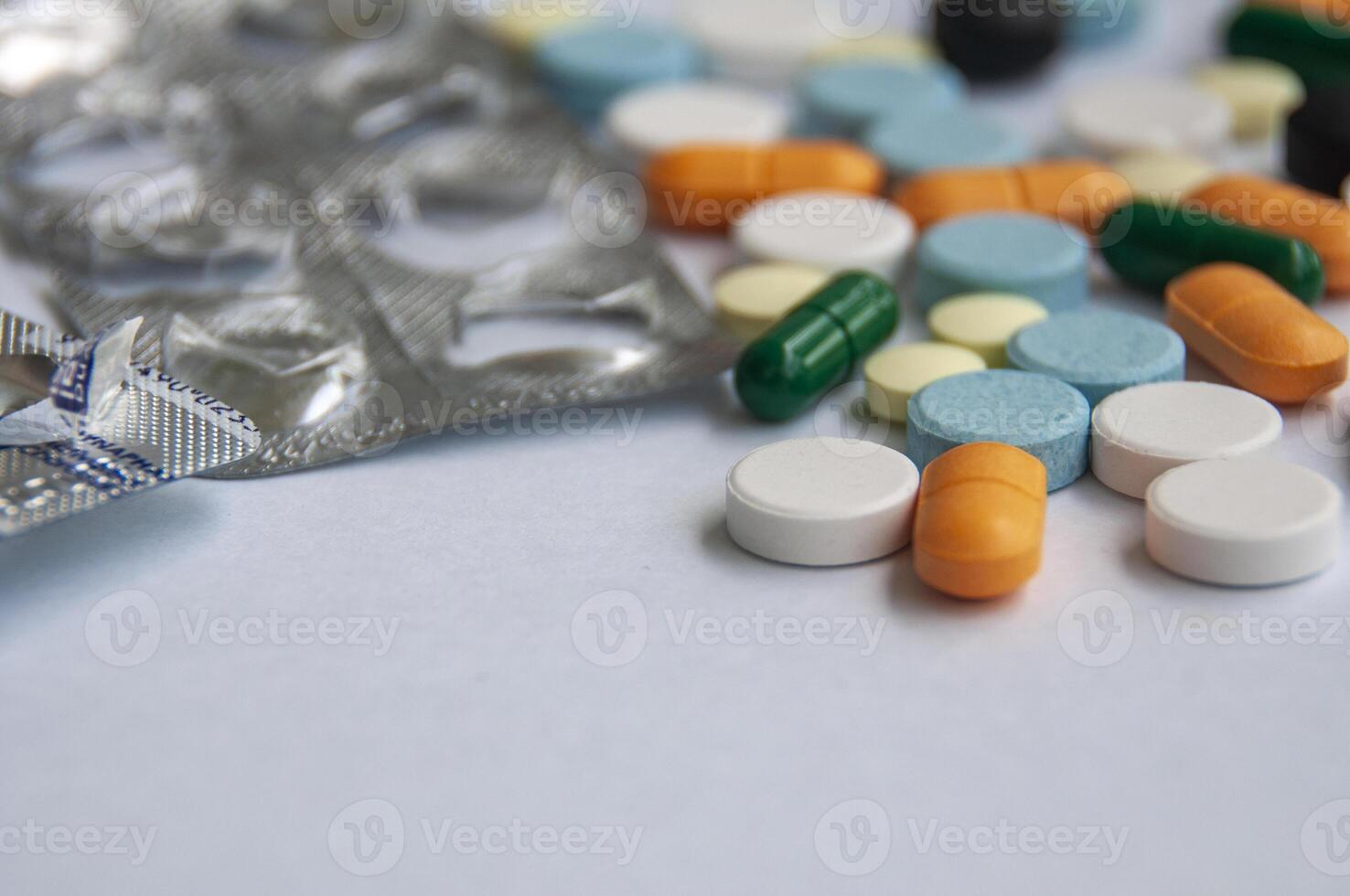 Variety of colorful pills and capsules scattered on a light colored surface with customizable space for text. photo