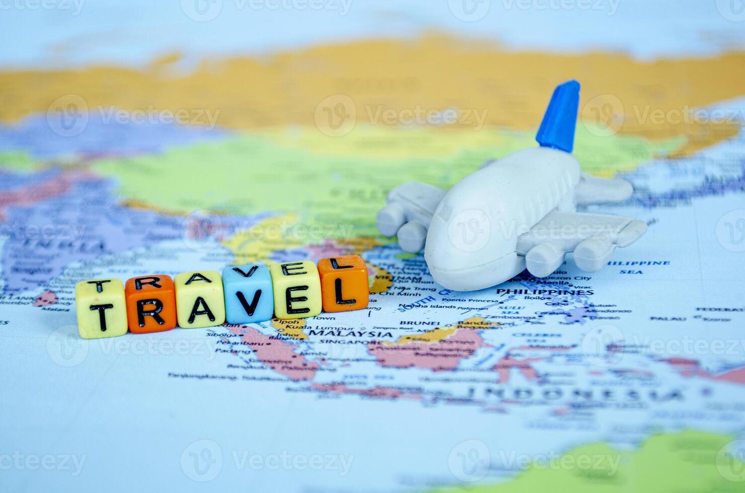 Small plastic cube with text TRAVEL and a small airplane placed on a world map representing travel or global exploration photo