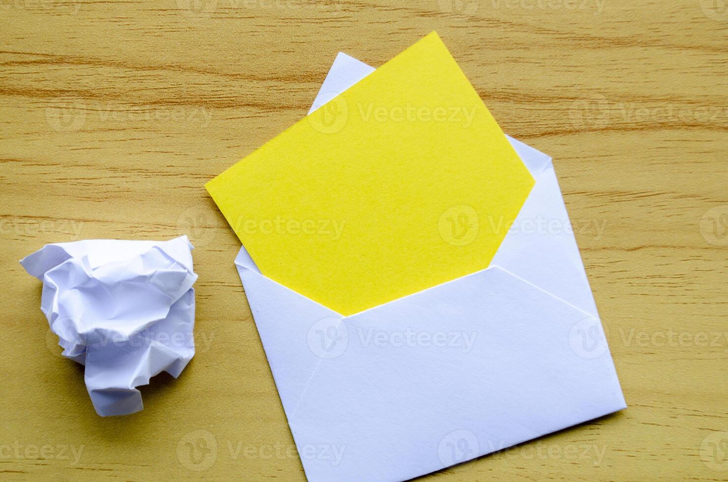 Top view of empty yellow notepad inside an envelope with crumpled paper with customizable space for text photo