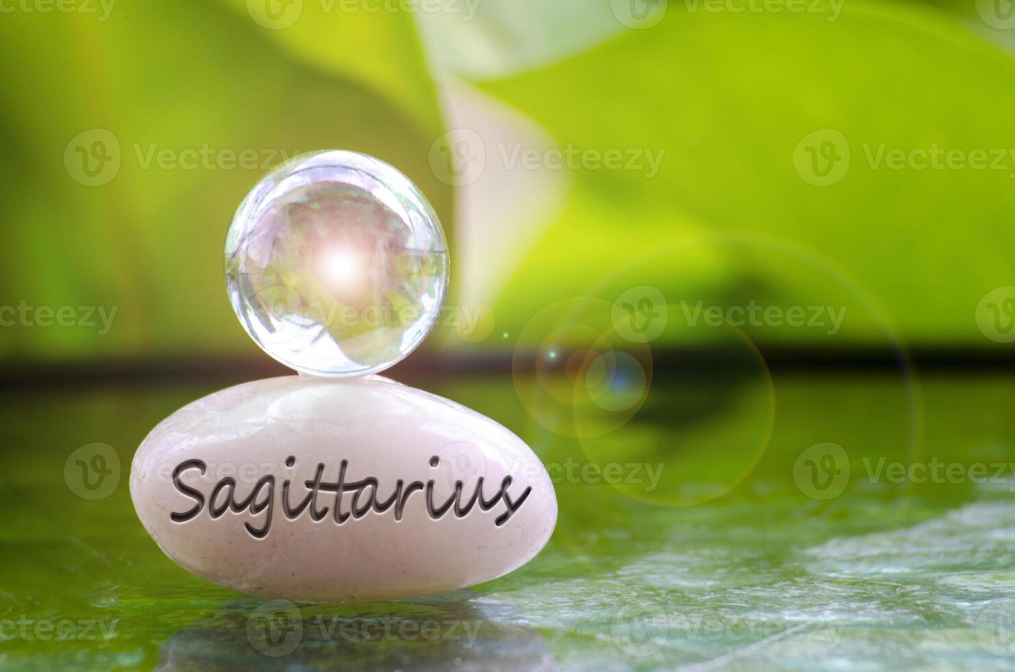 Sagittarius text engraved on Zen stone with shining glass marble on top. Zodiac concept photo