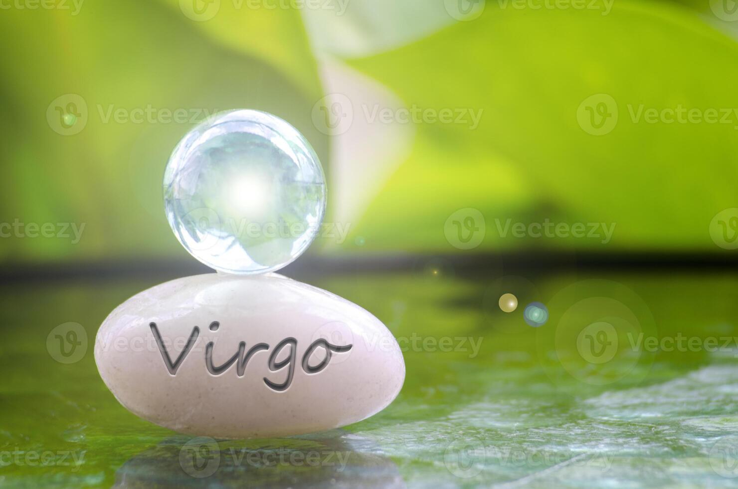 Virgo text engraved on Zen stone with shining glass marble on top. Zodiac concept photo