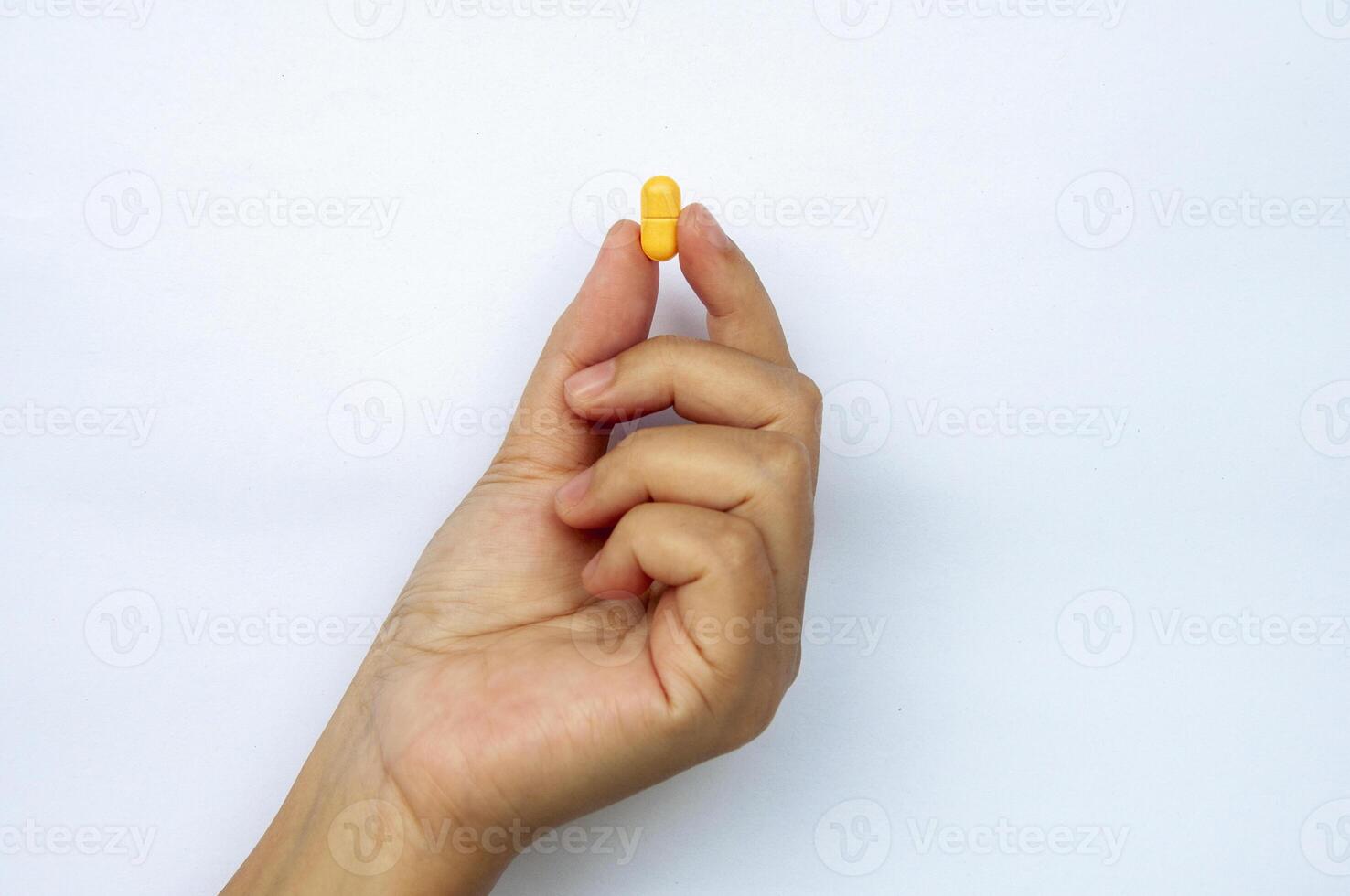 Hand holding yellow pill or capsules with customizable space for text. Medical and health matters concept photo