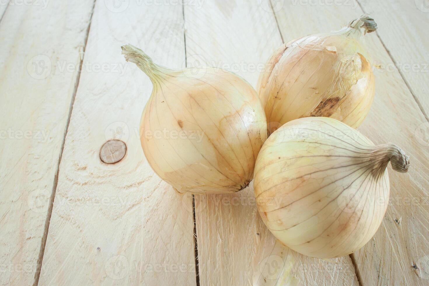 three onions on a wooden table photo