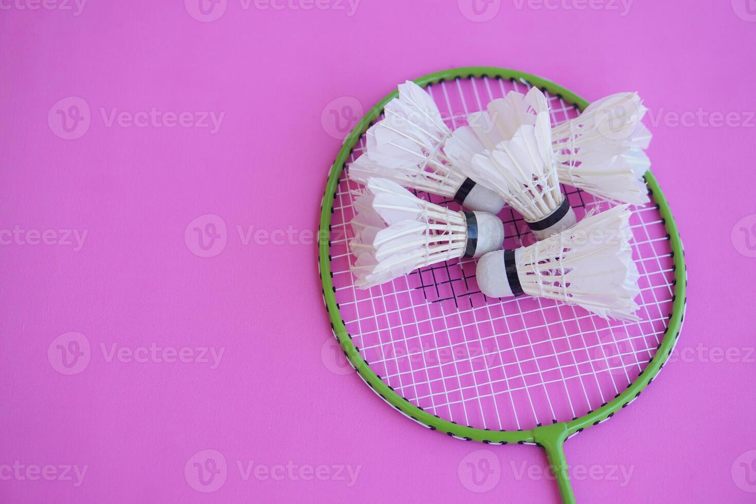 Shuttlecock and rackets. Badminton sport equipment on pink background. Concept, sport, exercise, recreation activity for good health. Popular sport for all genders photo