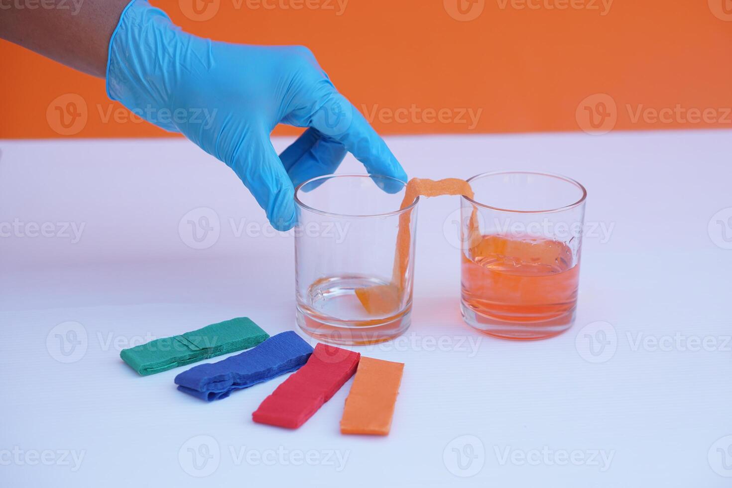 Hand holds glass of water and colorful stripes paper. Equipment for doing science experiment about chromatography. Concept, Easy activity chemistry lesson for kid. photo