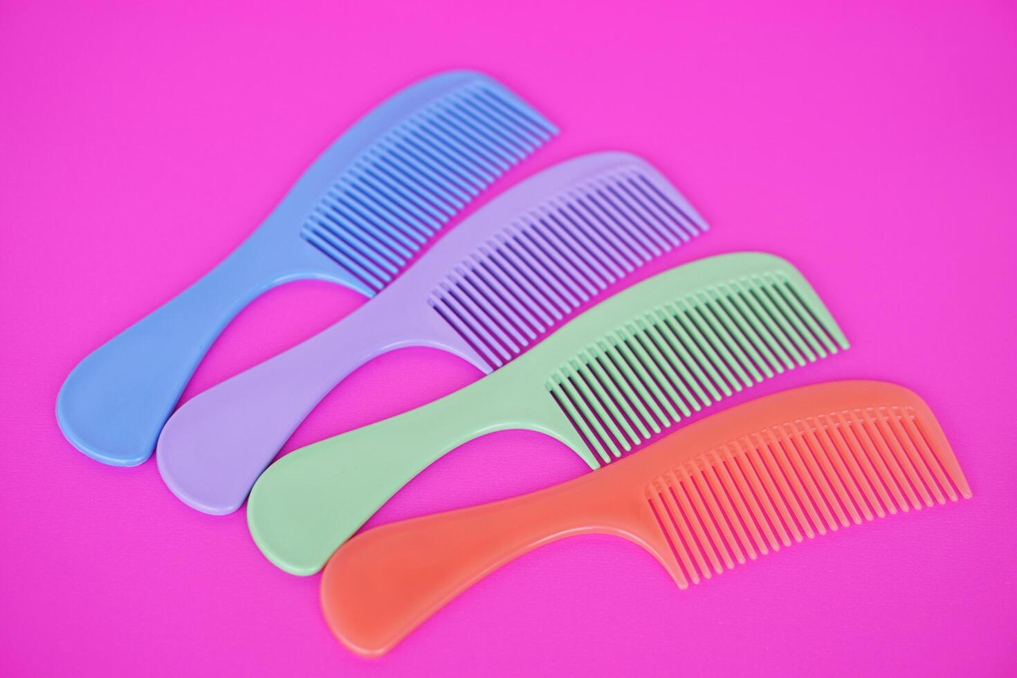 Colorful plastic hair combs with handle isolated on pink background. Concept , equipment or tool for hair beauty or decoration. photo