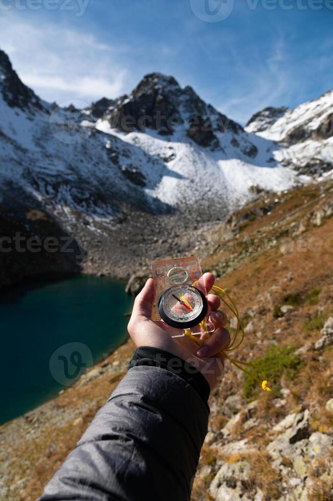 Man explorer looking for direction with compass in summer mountains, first person view of man hand with modern compass photo