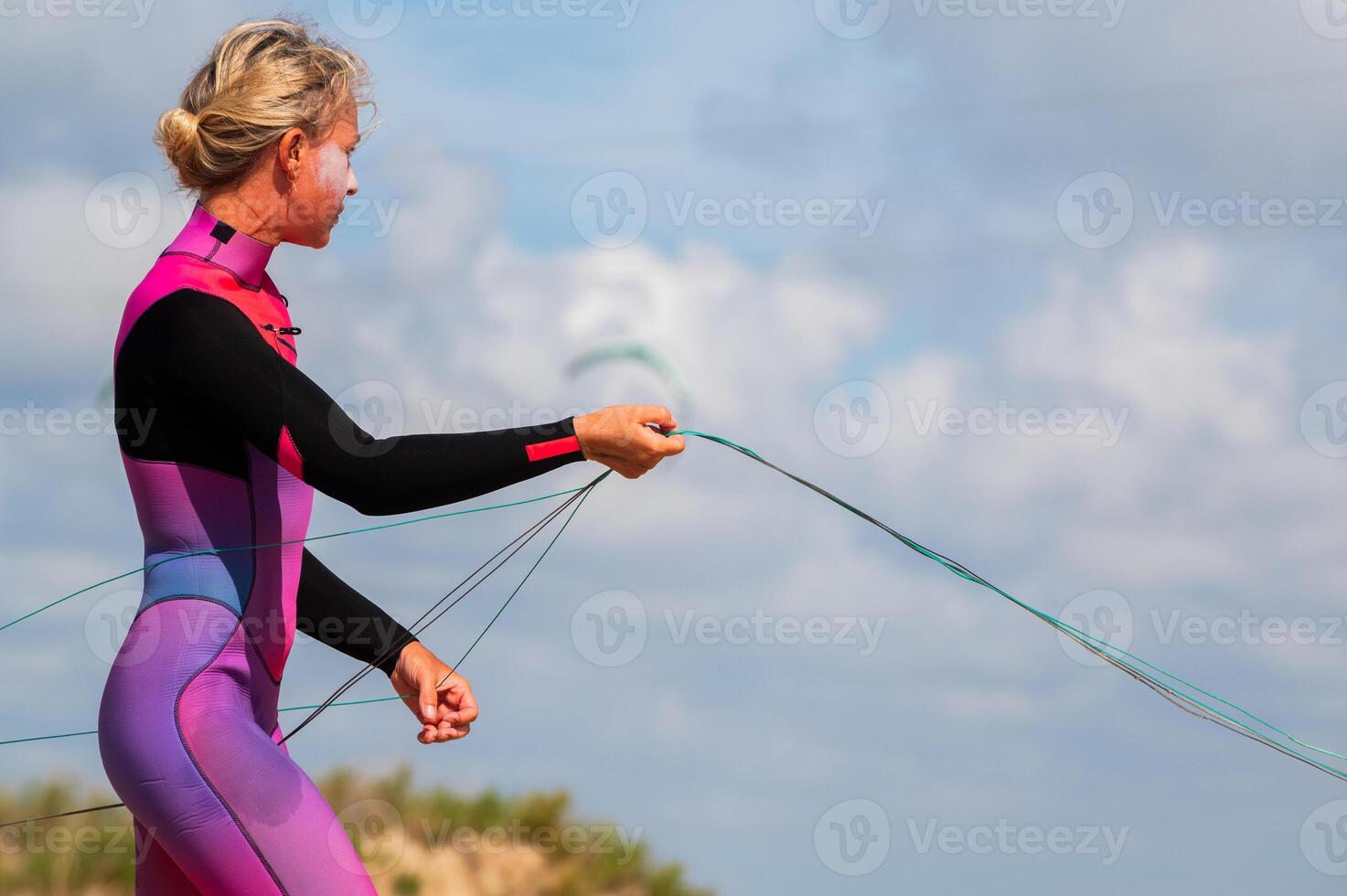 A young female kitesurfer unwinds and straightens the lines of her kite before riding. Preparing the kite for kitesurfing photo