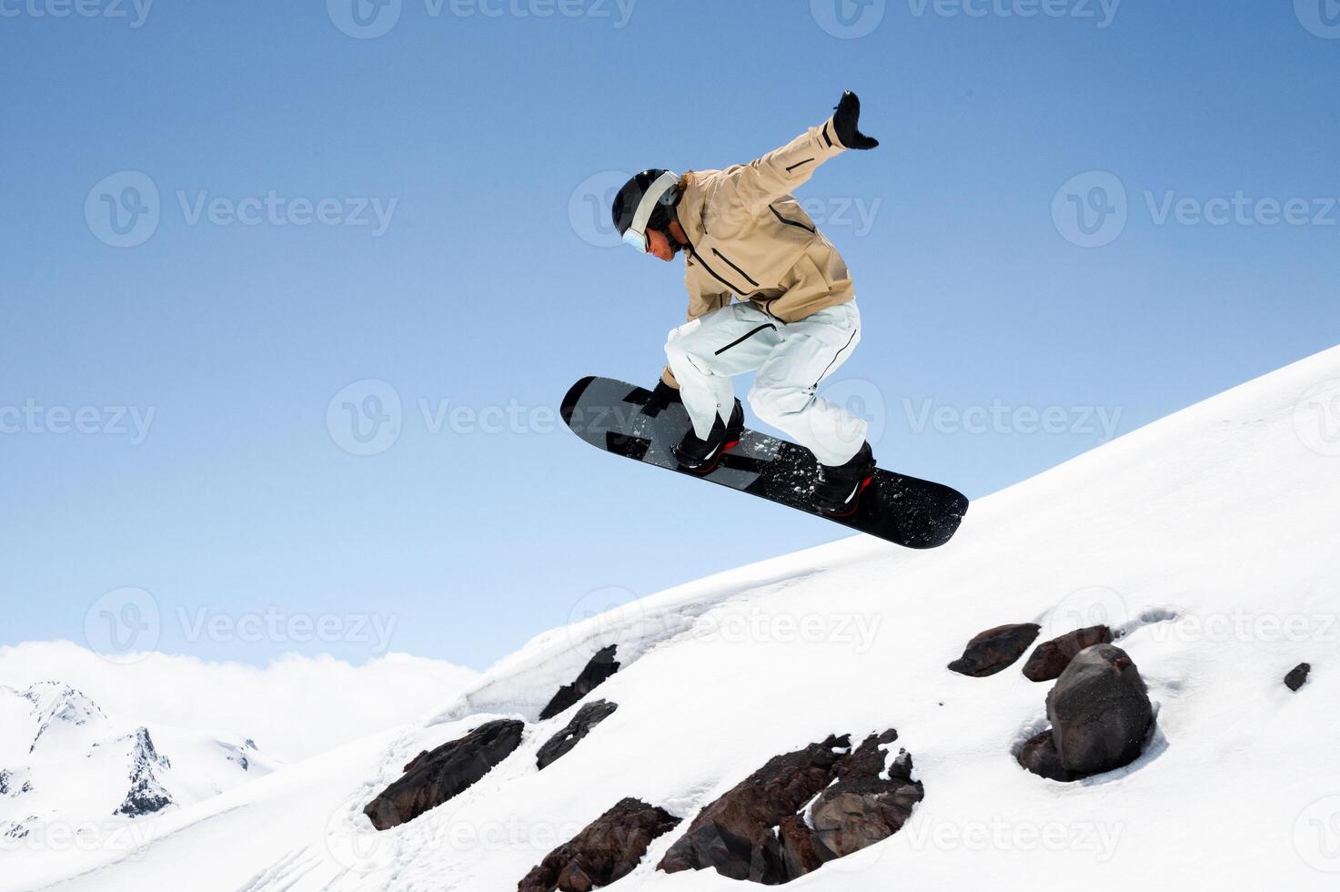 athlete man performing tricks on snowboard, exuding confidence and control in vibrant winter gear against clear skies and alpine scenery. Concept of extreme sport, ski-resort, holidays photo