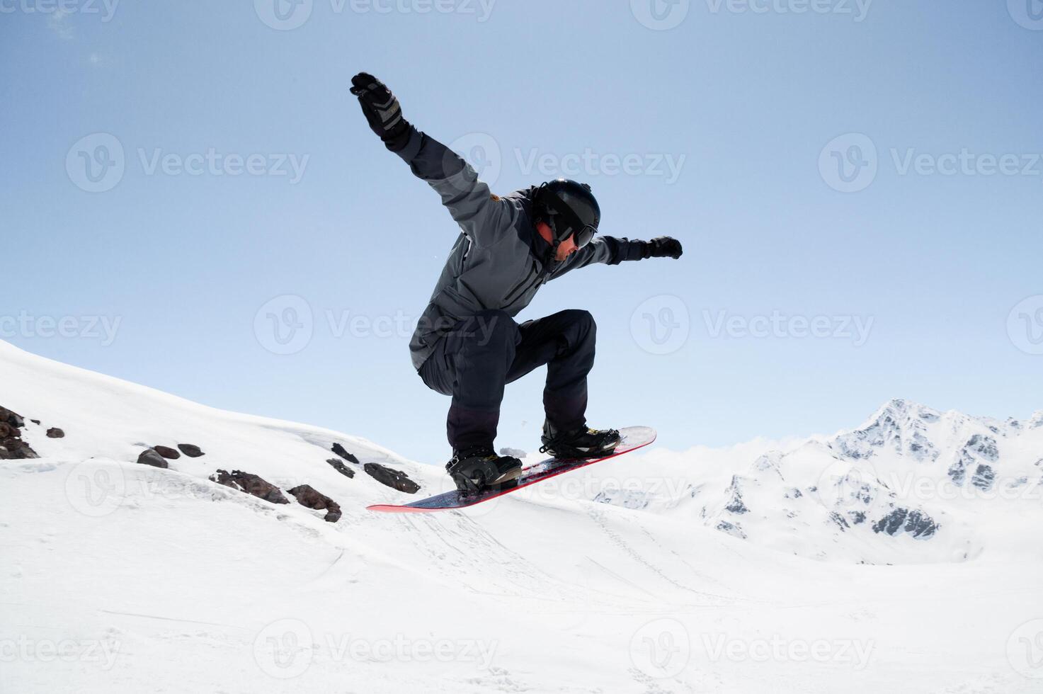 Beginner snowboarder riding on sunny day, performing trick in air. Sport tourist snapshot while snowboarding during winter vacation photo