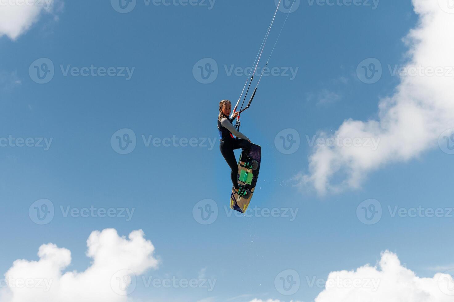 Girl-kayv d jump makes a trick with a grab against the background of a blue sky and clouds photo