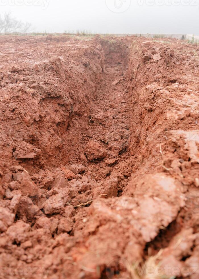 Deep Trench in Red Soil on Misty Day photo