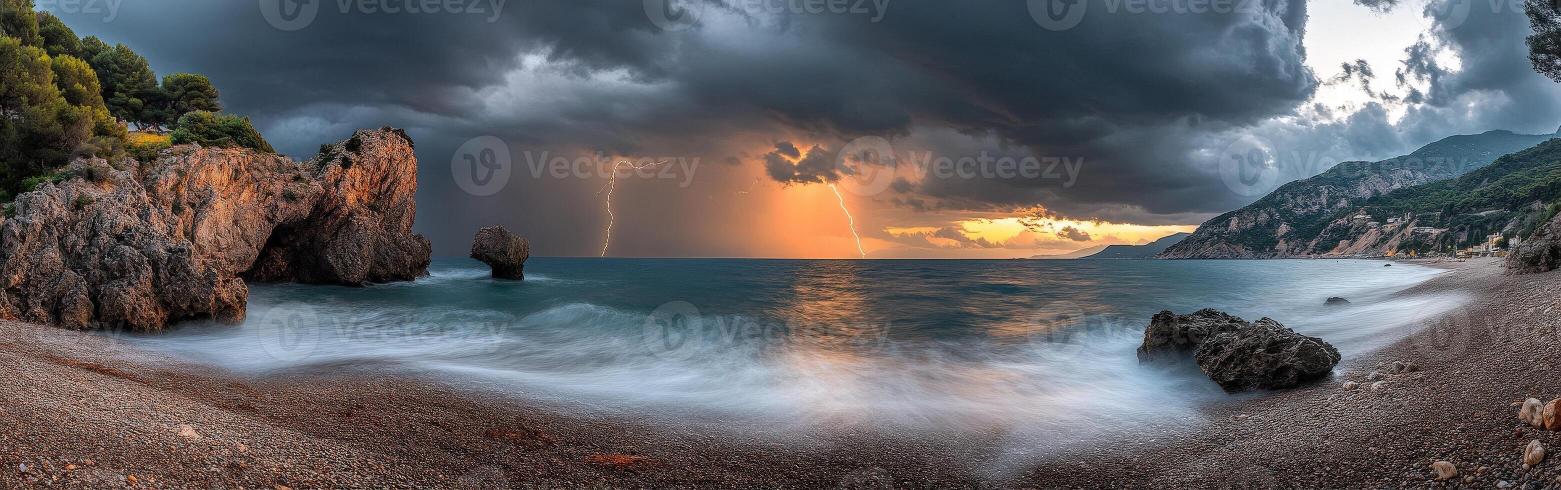 A stormy sunset over the ocean with rocks and water photo