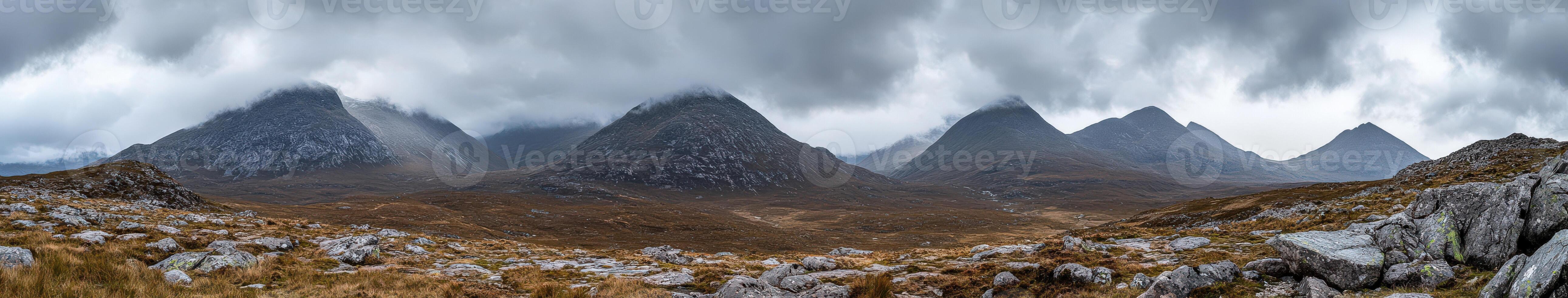 A mountain range with clouds and rocks in the foreground photo