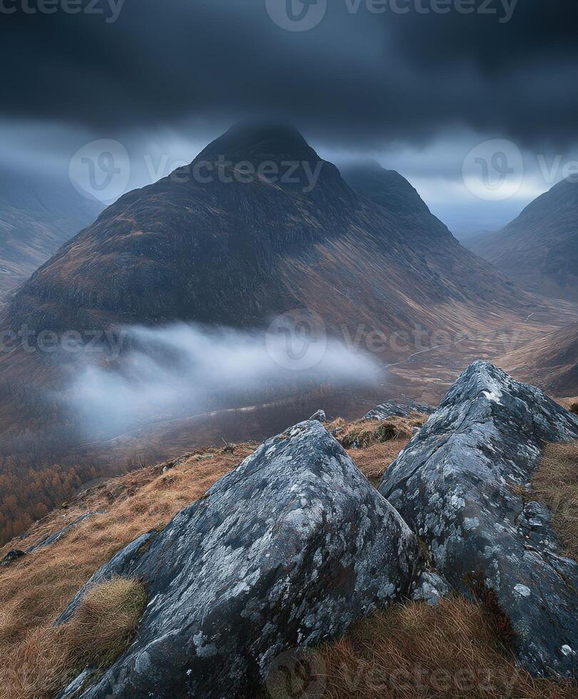 A mountain range with a large rock in the foreground photo