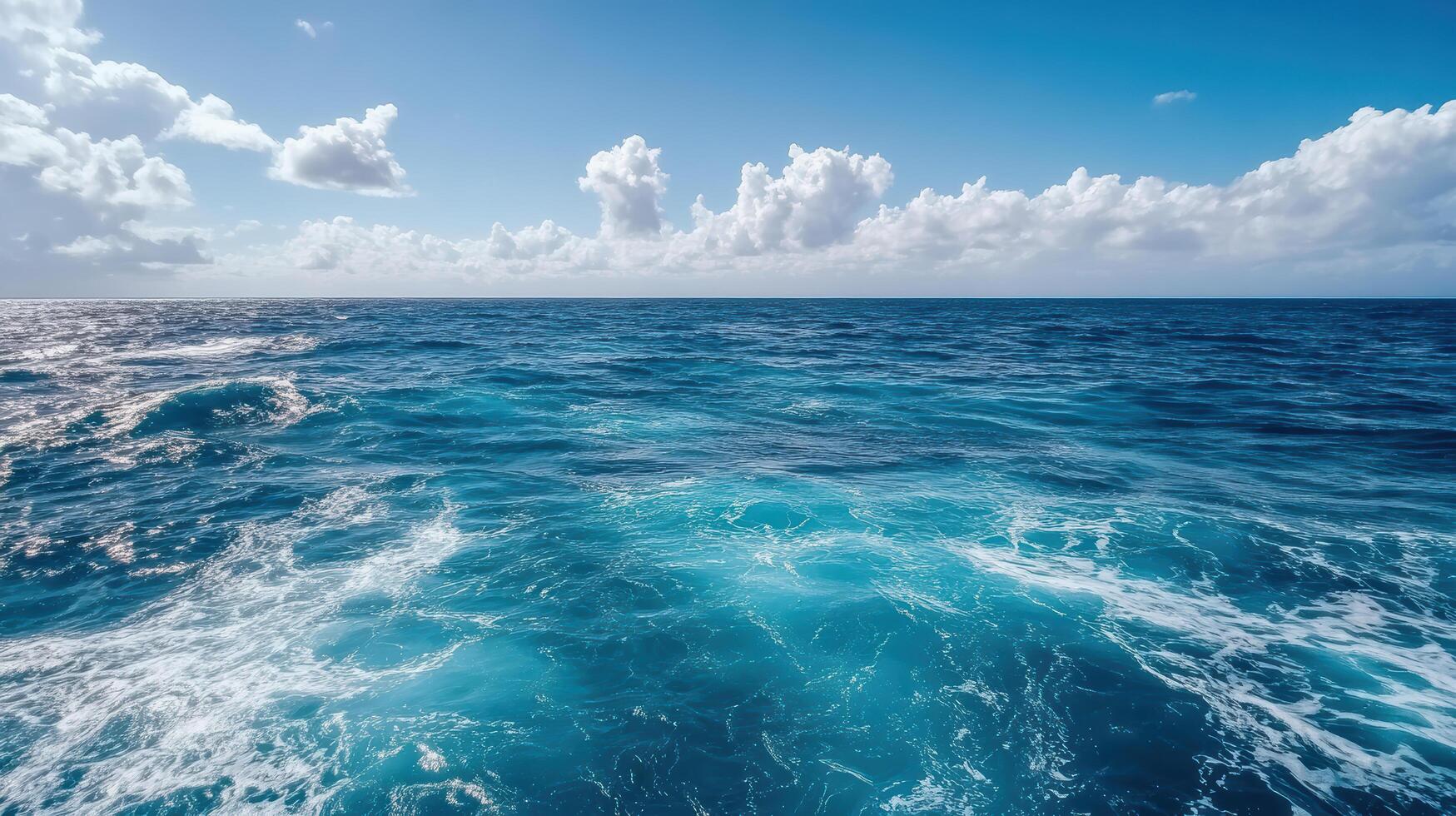 Vibrant ocean waves under clear blue sky with fluffy clouds photo