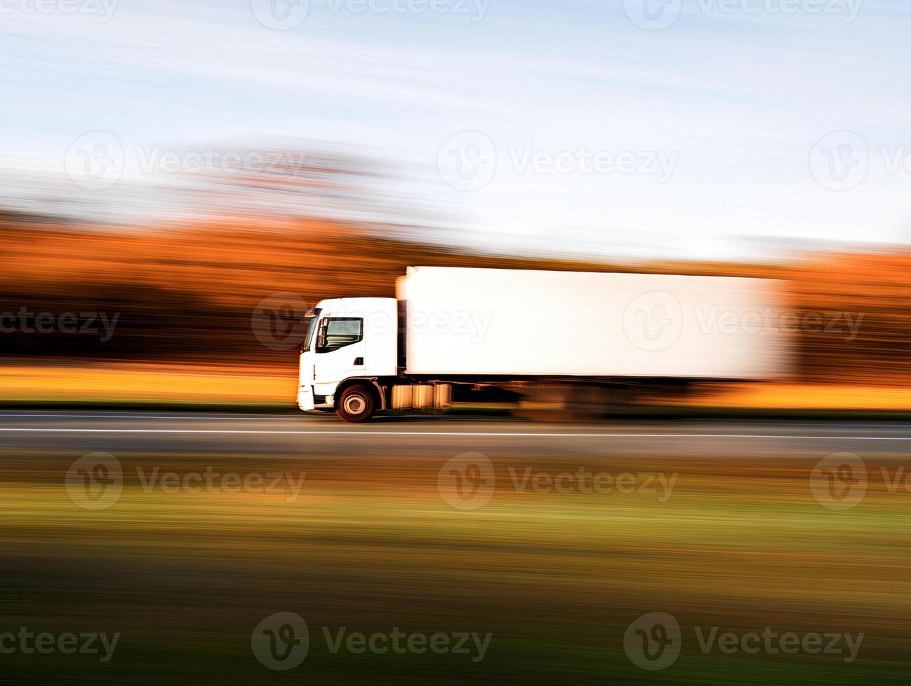Truck driving fast along a highway in autumn scenery photo