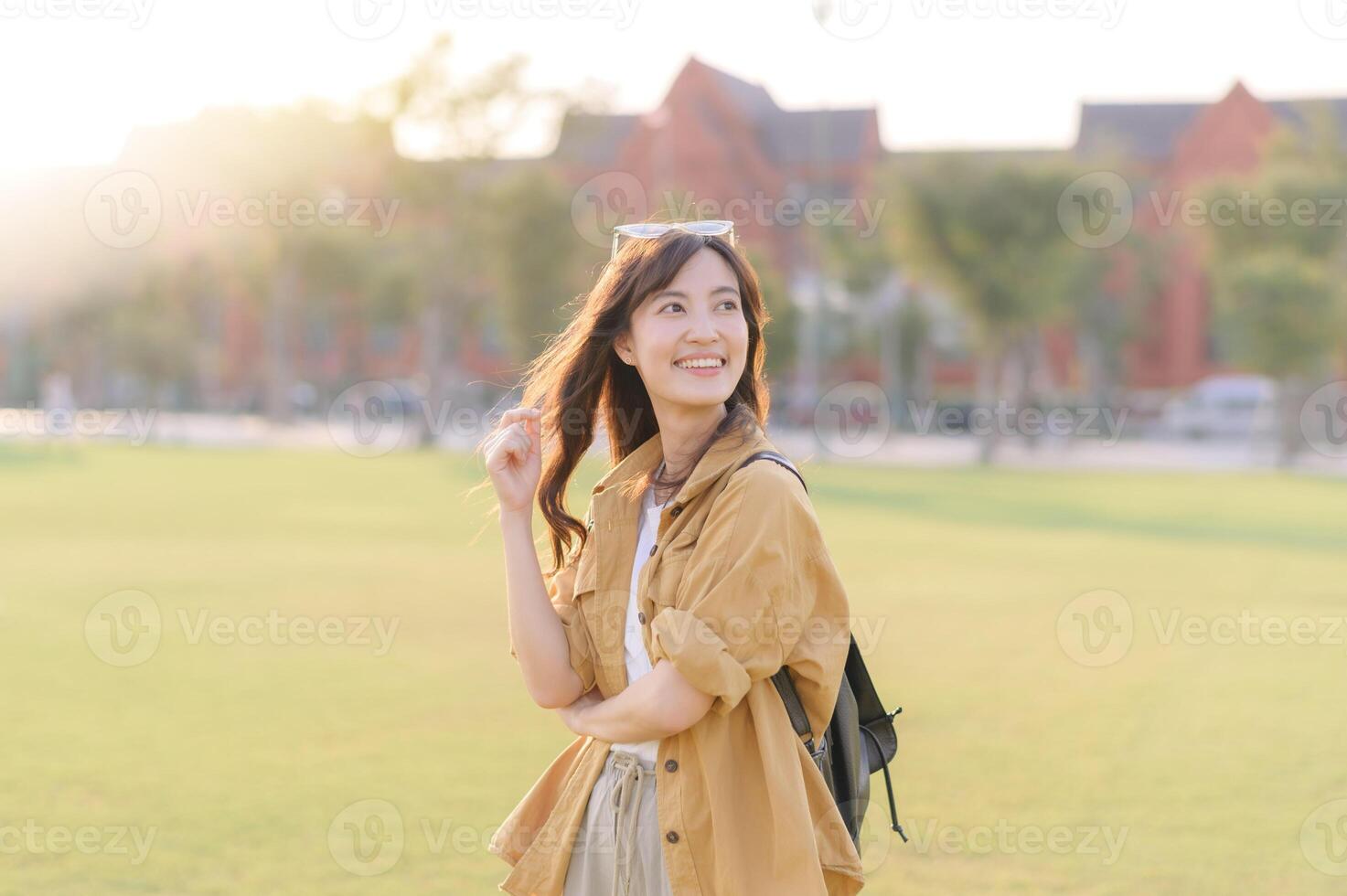 Asian woman in yellow jacket and white pants standing in grass photo