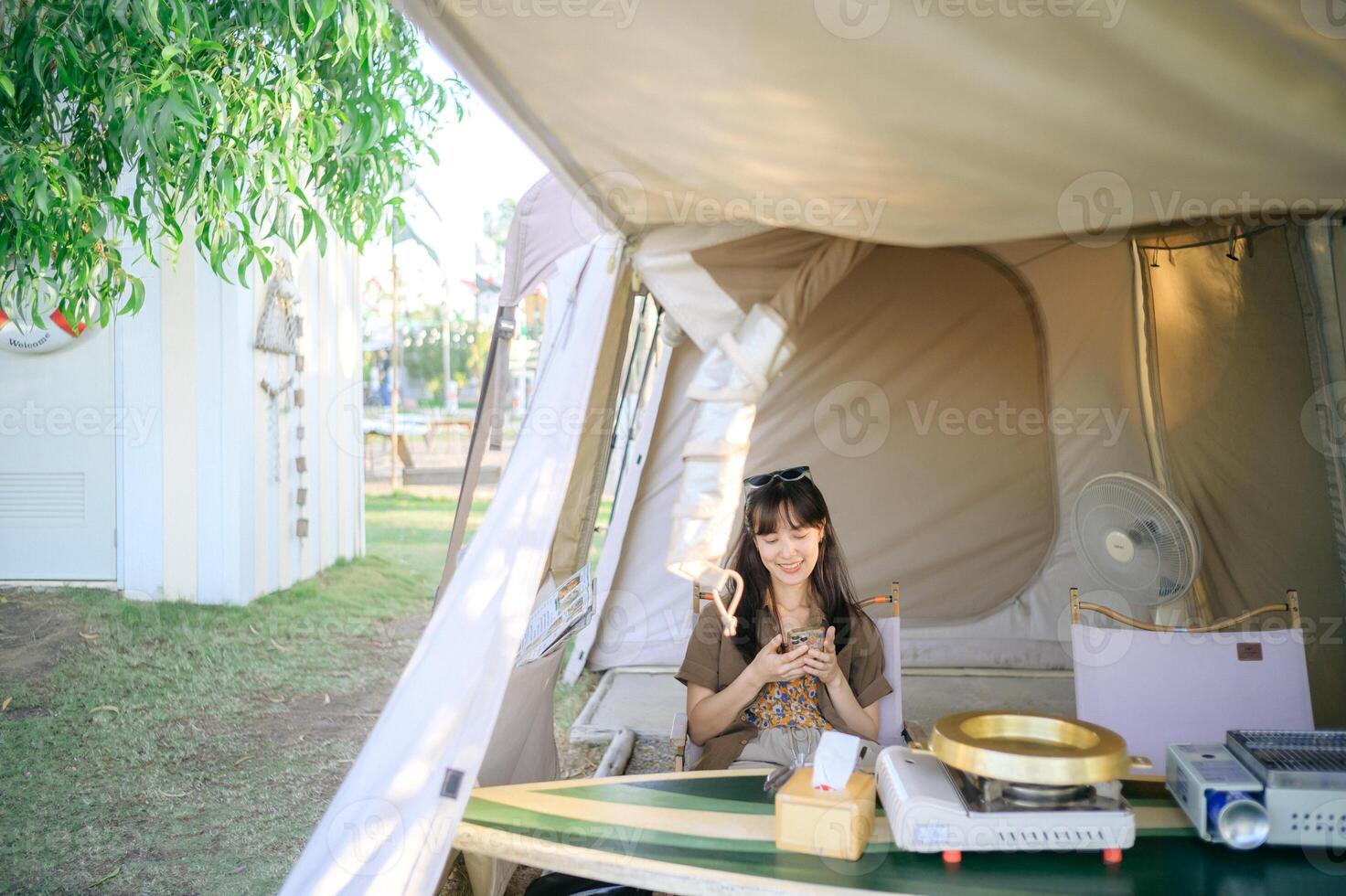 A woman sitting in a tent using a cell phone photo