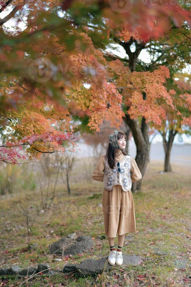 A girl in a brown dress standing in front of a tree photo