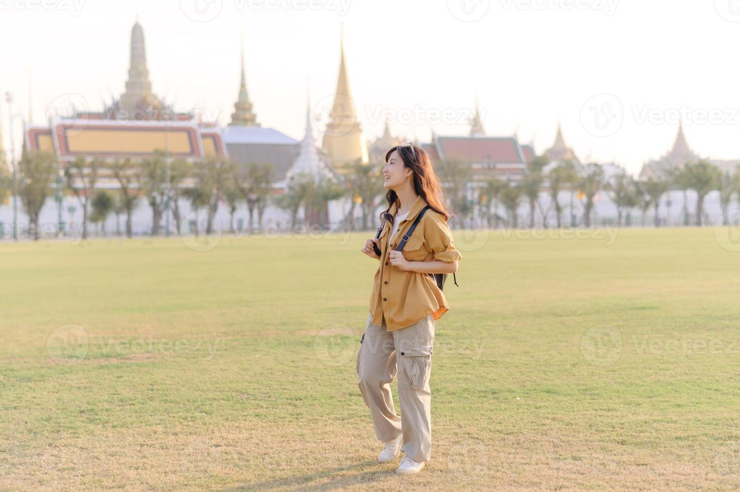 A woman in a yellow shirt is standing in front of a building photo