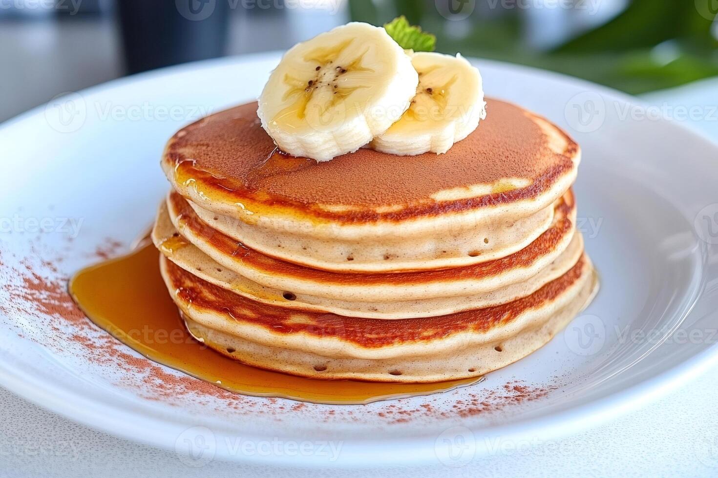Stack of pancakes with sliced banana, honey and cinnamon on white plate photo