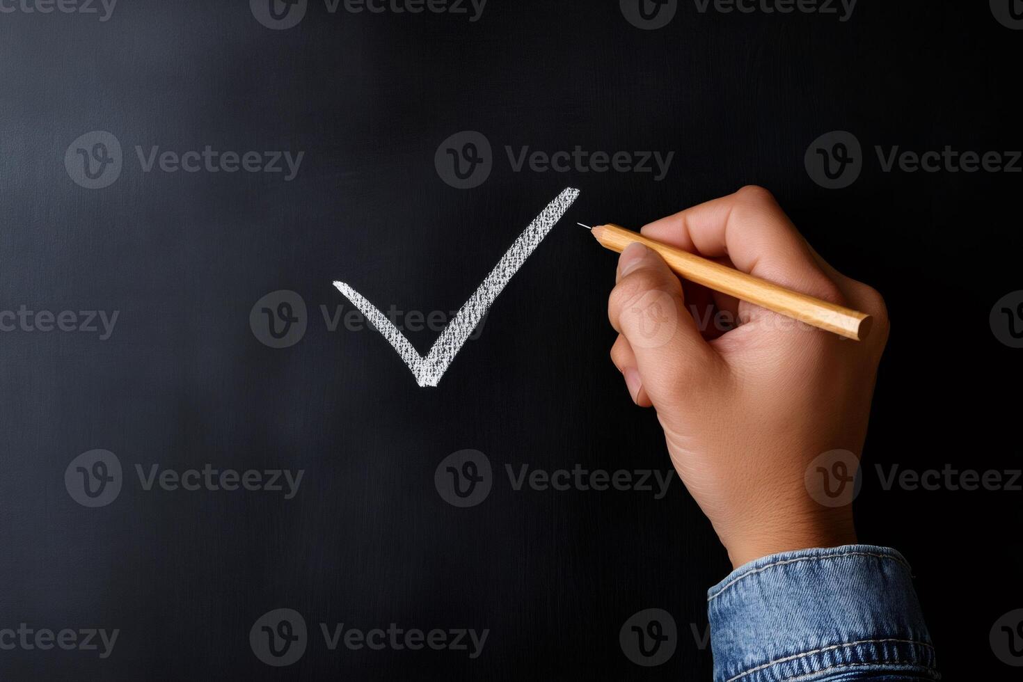 Teacher drawing check mark symbol on blackboard with chalk photo