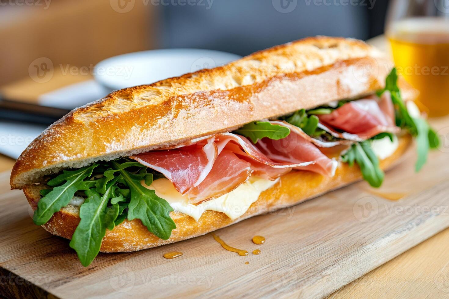Delicious baguette sandwich with prosciutto, cheese and arugula on wooden board photo