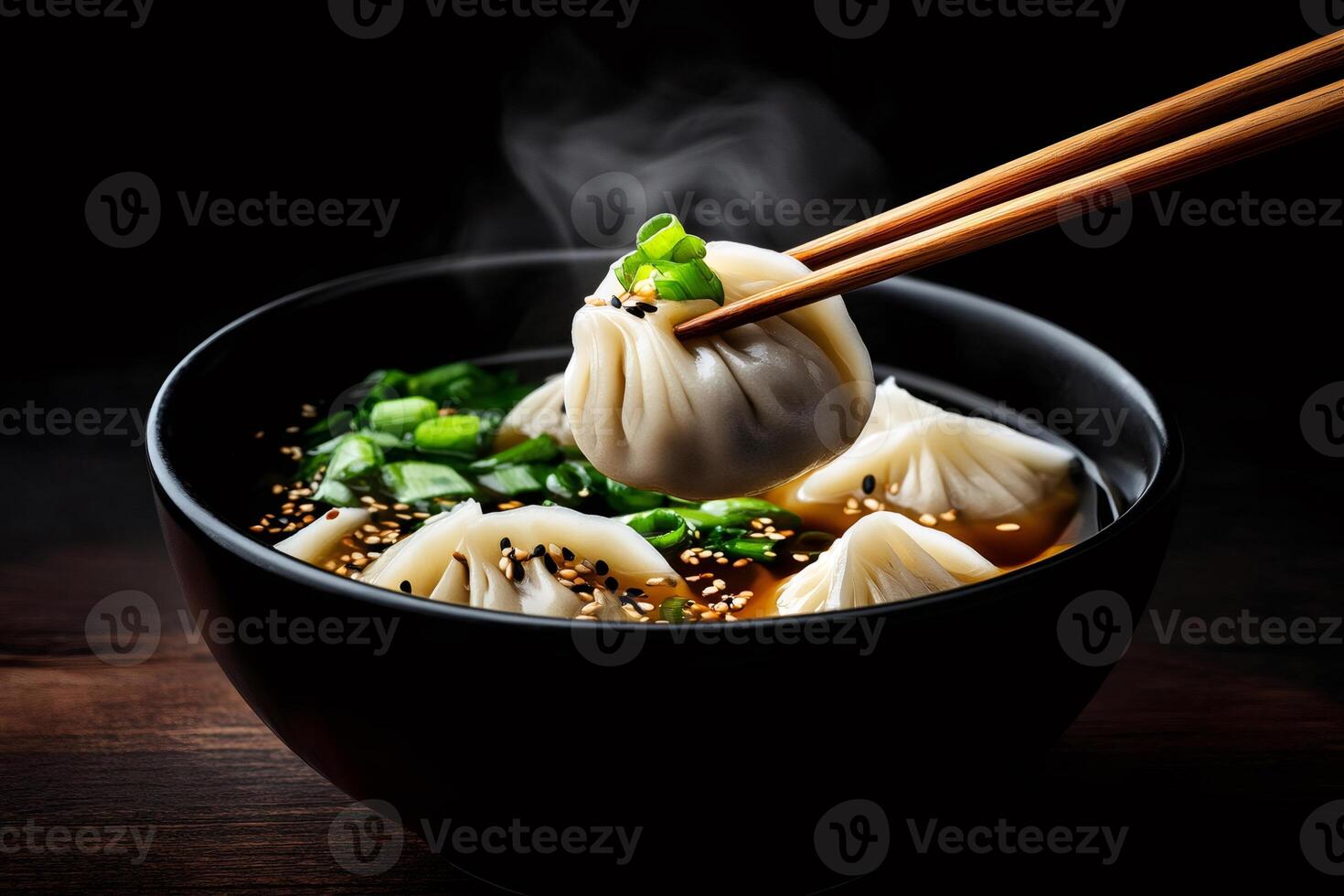 Steaming hot dumplings being lifted from broth with chopsticks photo