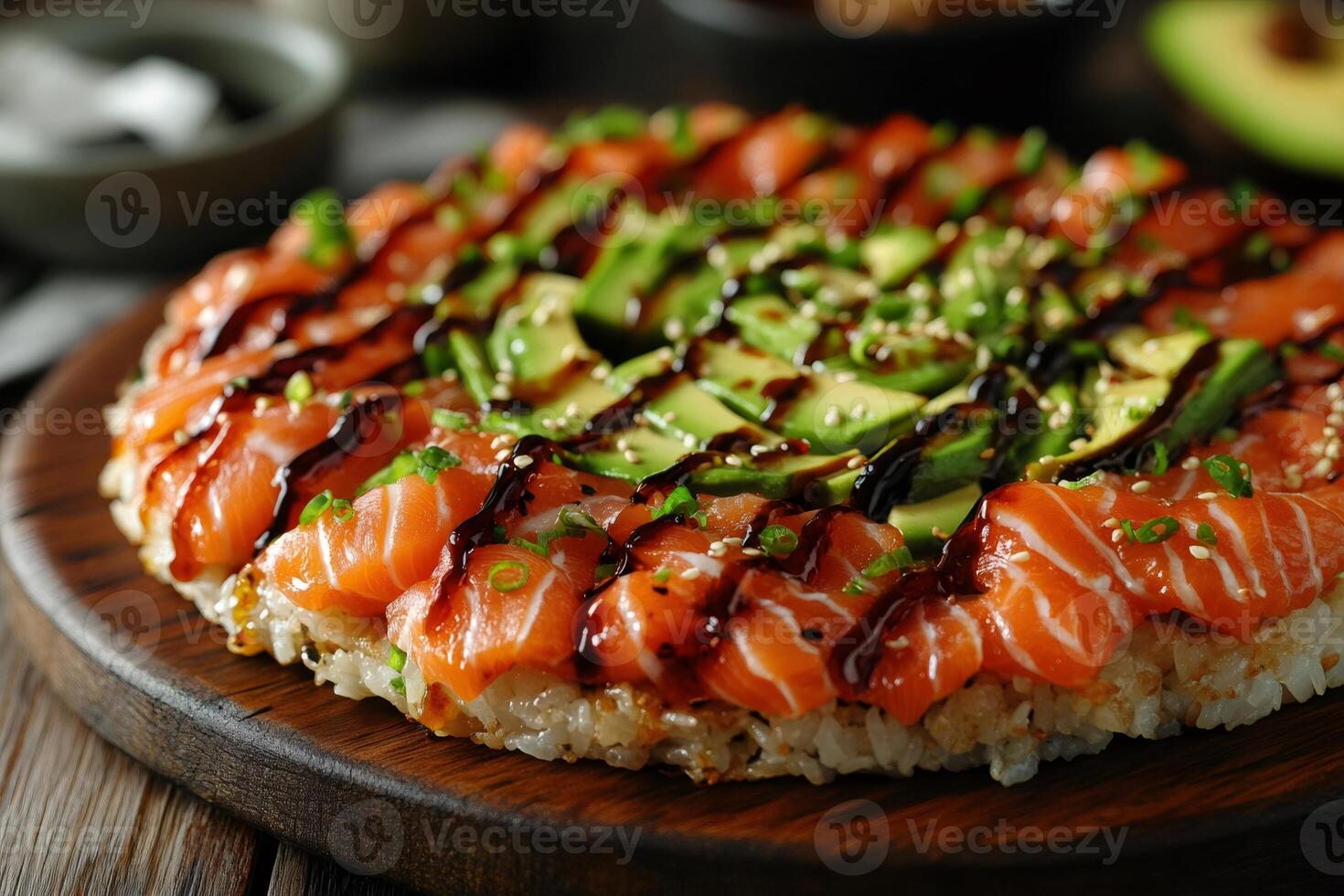 Sushi pizza with salmon, avocado, and sesame seeds rests on wooden board photo