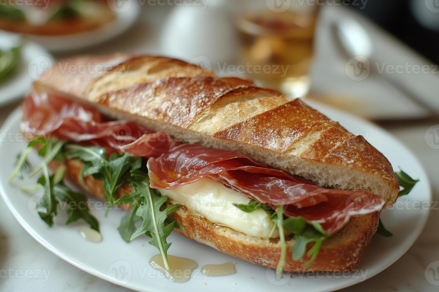 Delicious baguette sandwich with prosciutto, cheese and arugula on white plate photo