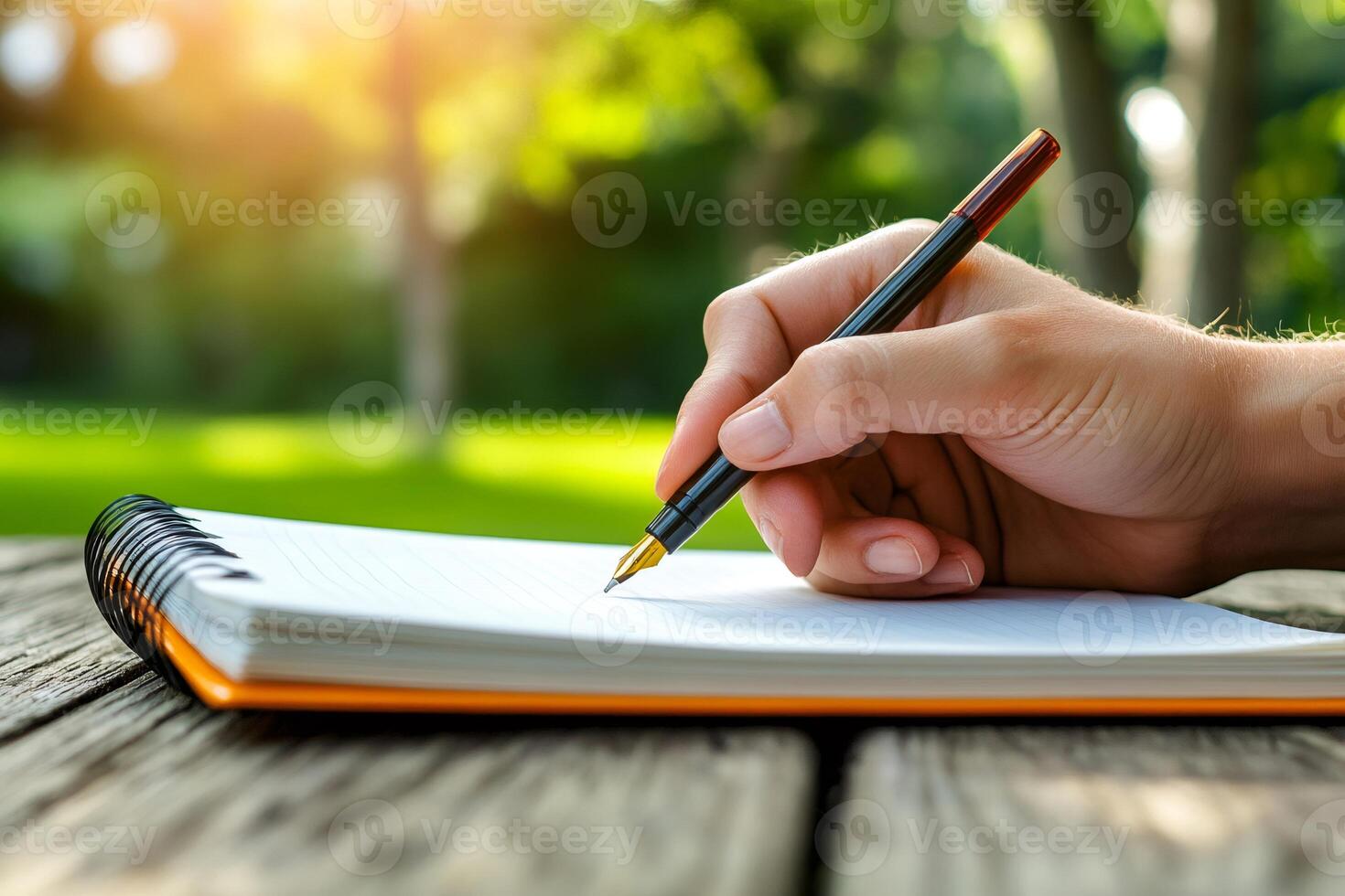 Writer using fountain pen taking notes in notebook outdoors in park photo