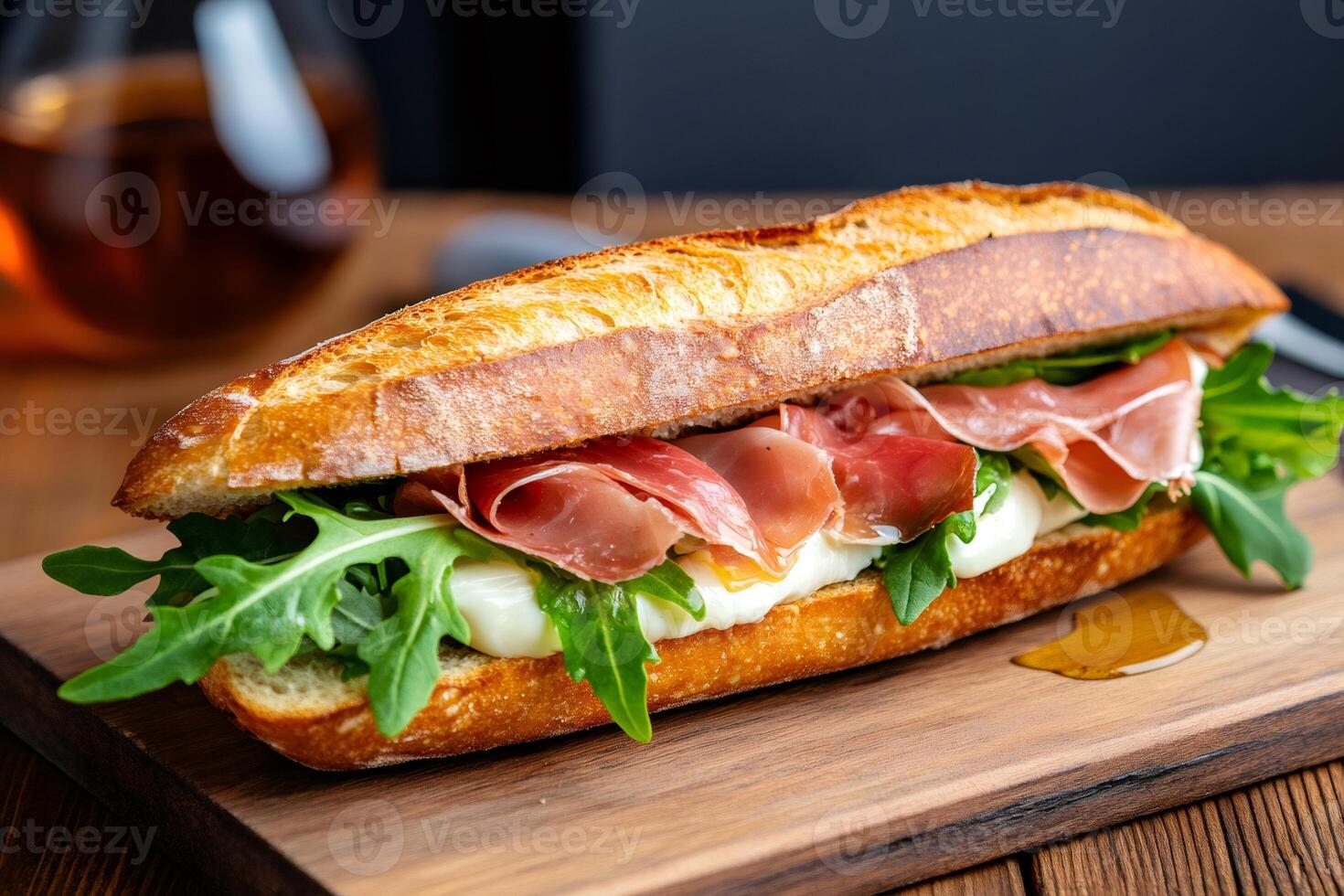 Delicious baguette sandwich with prosciutto, arugula, and mozzarella cheese on wooden board photo