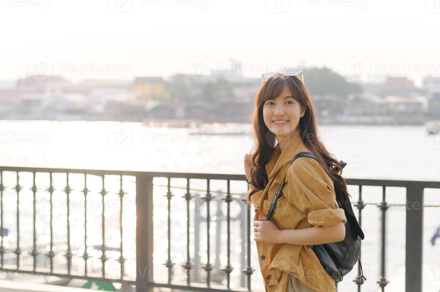 Asian woman with backpack standing on a bridge photo