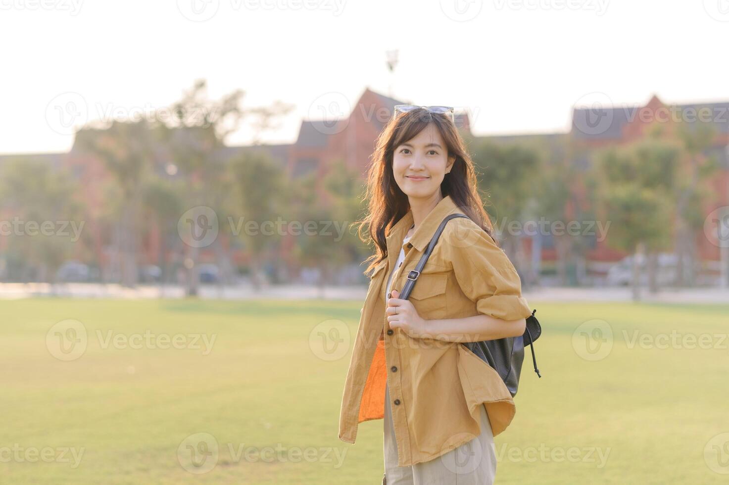 Asian woman with backpack standing in grassy field photo