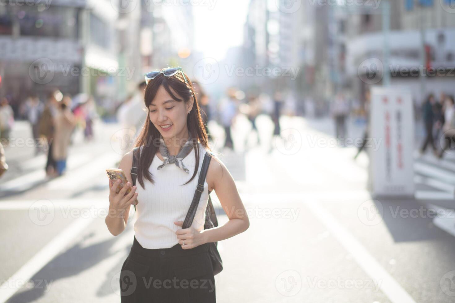 Tokyo smiles, A joyful woman in Tokyo, using her smartphone amidst the bustling urban environment. photo