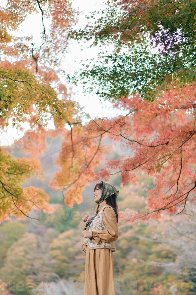 A woman in a long coat standing in the middle of a forest photo
